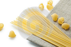 Different sort of macaroni shells and spaghetti on brown napkin