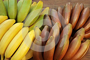 Different sorts of bananas on wooden table, closeup