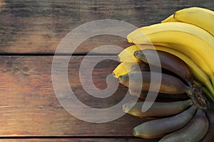 Different sorts of bananas on wooden table, top view. Space for text