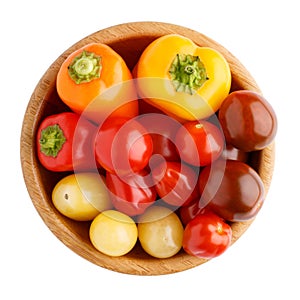 Different sorts of cherry tomatoes and multi colored little sweet peppers in wooden bowl isolated on white background. Top view