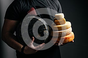 Different sorts of hard cheese wheels in the hands of a cheesemaker, dairy products