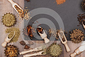Different spices in bakeware with wooden scoops on the slate slone background