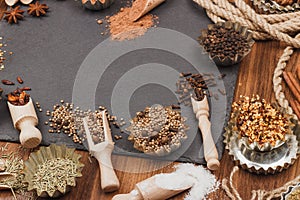 Different spices in bakeware with wooden scoops on the slate slone background