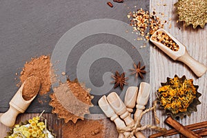 Different spices in bakeware with wooden scoops on the slate slone background