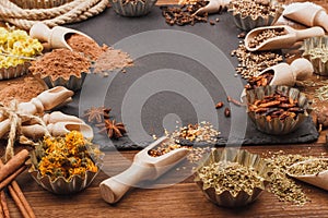 Different spices in bakeware with wooden scoops on the slate slone background