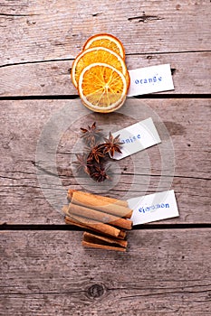 Different spices - cinnamone, slices of dried orange, anise and tag with their names on vintage wooden  background. photo