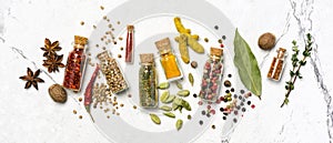 Different spices, dry kitchen herbs and seeds in glass vials for tasty meals