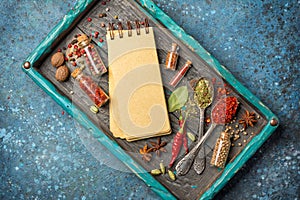 Different spices, dry kitchen herbs and seeds for tasty meals and mock-up of craft paper notebook