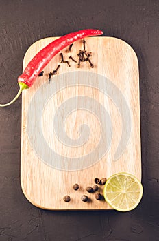 Different spices and empty cutting board/ Different spices and empty cutting board on a dark background. Top view. Copy space