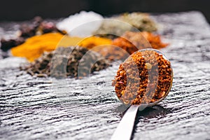 Different spices and herbs on a black slate. Iron spoon with chili pepper. Indian spices. Ingredients for cooking. Healthy eating