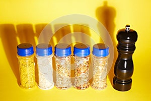 Different spices in jars and black pepper