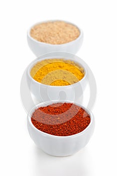 Different spices in white bowls isolated on white background.