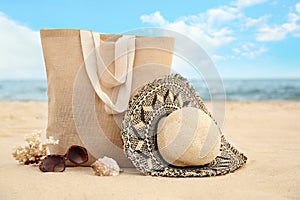 Stylish beach objects, coral and seashell on sand near sea