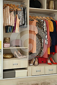 Different stylish women`s clothes on hangers in wardrobe