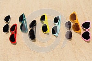 Different sunglasses on beach sand
