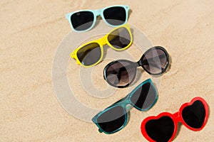 Different sunglasses on beach sand