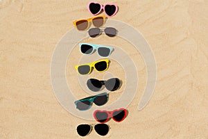 Different sunglasses on beach sand