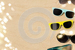 Different sunglasses on beach sand
