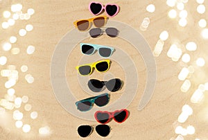 Different sunglasses on beach sand