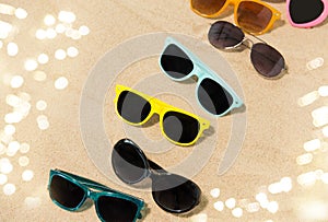 Different sunglasses on beach sand