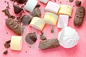 Different sweets on pink background: marshmallows, zephyr and chololate.