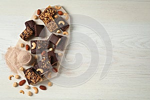 Different tasty energy bars, protein powder and nuts on white wooden table, flat lay. Space for text