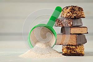 Different tasty energy bars and protein powder on white table, closeup