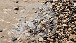 Different texture on the beach - water and sand, stones and pebbles, waves and splashes