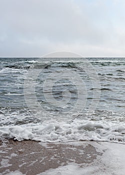 Different texture on the beach - water and sand, stones and pebbles, waves and splashes