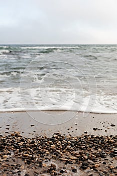 Different texture on the beach - water and sand, stones and pebbles, waves and splashes