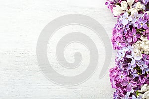 Different  tiny flowers of Lilac on the  white wooden shabby background. Floral border. Flat lay