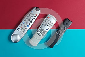 Different TV remotes on a red-blue background.