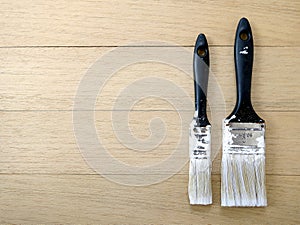 different two paintbrush with white color stain and size number on wooden plank floor