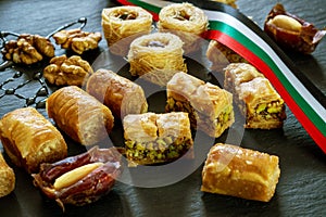 Different type of arabian baklava and dates on black background with space for text types - borma nest ush-el-bul-bul