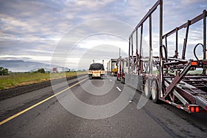 Different type of big rigs semi trucks and semi trailers running on the divided highway road early morning