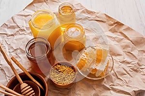 Different types of bee honey, honeycomb, liquid and pollen bee products in jars on table