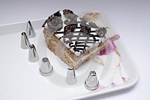 Different types of cake cream nozzels and a cake in a tray