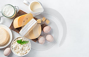 Different types of cheese, cottage cheese, sour cream and eggs on a gray background. Assortment of dairy products.