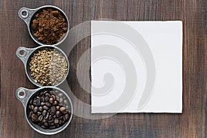 Different types of coffee and paper cadd on a wooden background