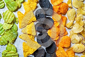 Different types of colored potato chips, gray background. Fast food concept