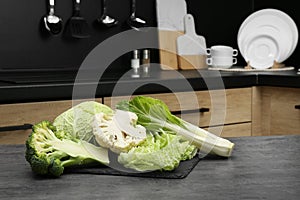 Different types of cut cabbage on grey table in kitchen