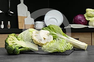 Different types of cut cabbage on grey table in kitchen