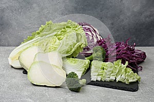 Different types of cut cabbage on light grey table