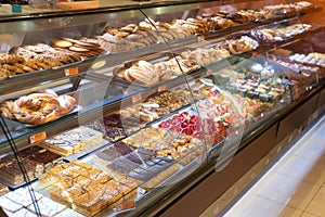 Different types of delicious cakes in pastry shop showcase.