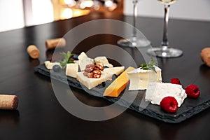 Different types of cheeses with berries and nuts on table