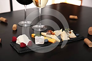Types of delicious cheeses with berries and nuts on table