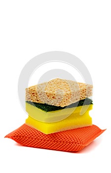 Different types of dish sponges, isolated on white background. Stacked orange, yellow and natural color sponges. Natural honeycomb