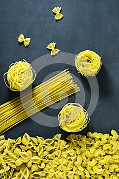 Different types of dry Italian pasta on a dark blue background.