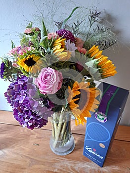 Colourful sunflowers, roses and hydrangas in a vase with champagne