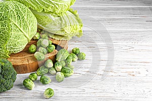 Different types of fresh cabbage on white wooden table, space for text